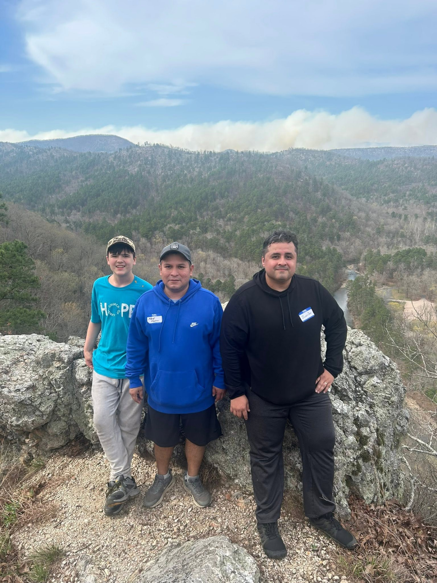 Three men standing at a rocky overlook above the valley